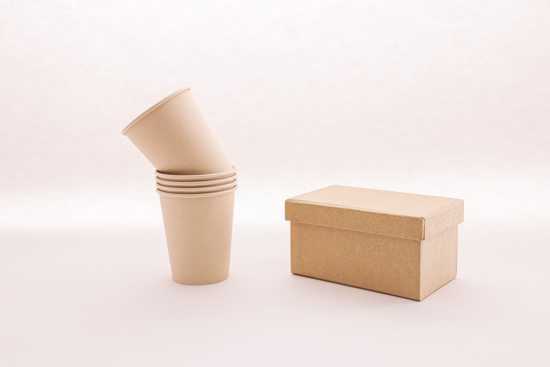 Stack of biodegradable takeaway boxes and paper cups on a wooden table